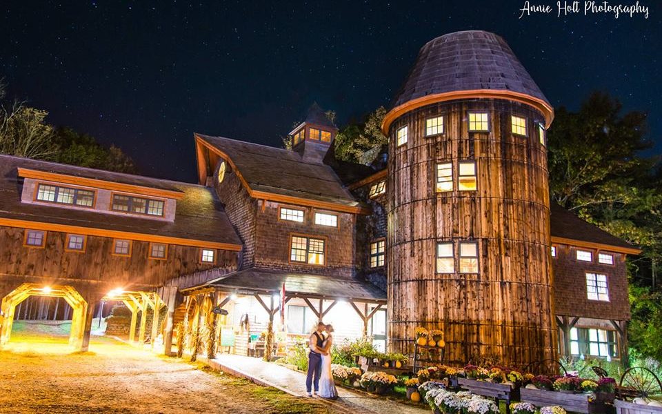 a bride and groom posing in front of Stonewall farm silo, at night in the fall