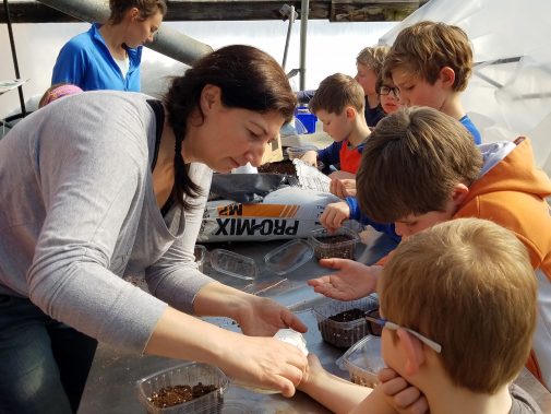 A lady showing children how to plant seeds